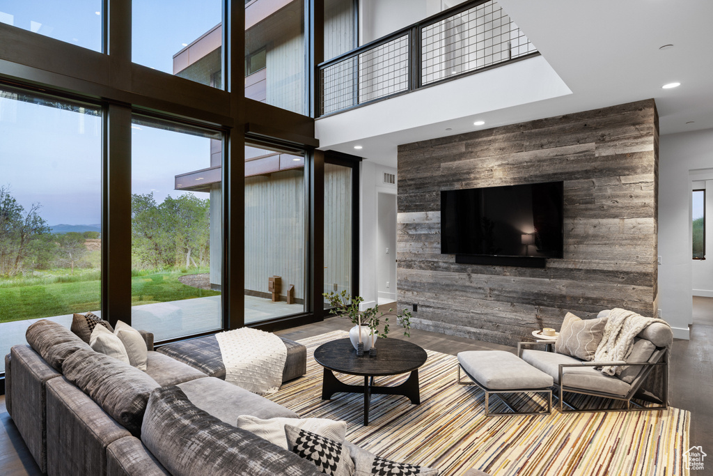 Living room with recessed lighting, wood finished floors, a high ceiling, and baseboards