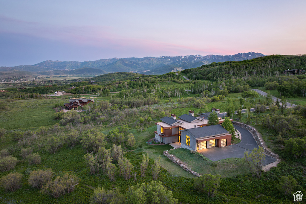 View of subject property featuring a mountain backdrop and a forest