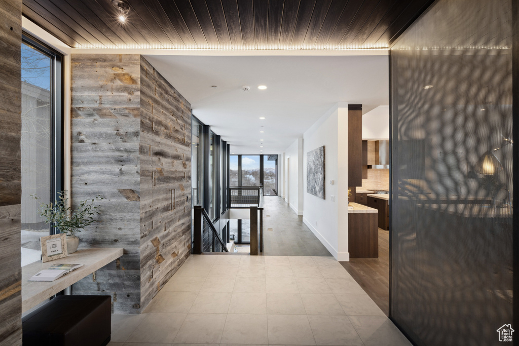 Hallway featuring an upstairs landing, recessed lighting, a wall of windows, and baseboards