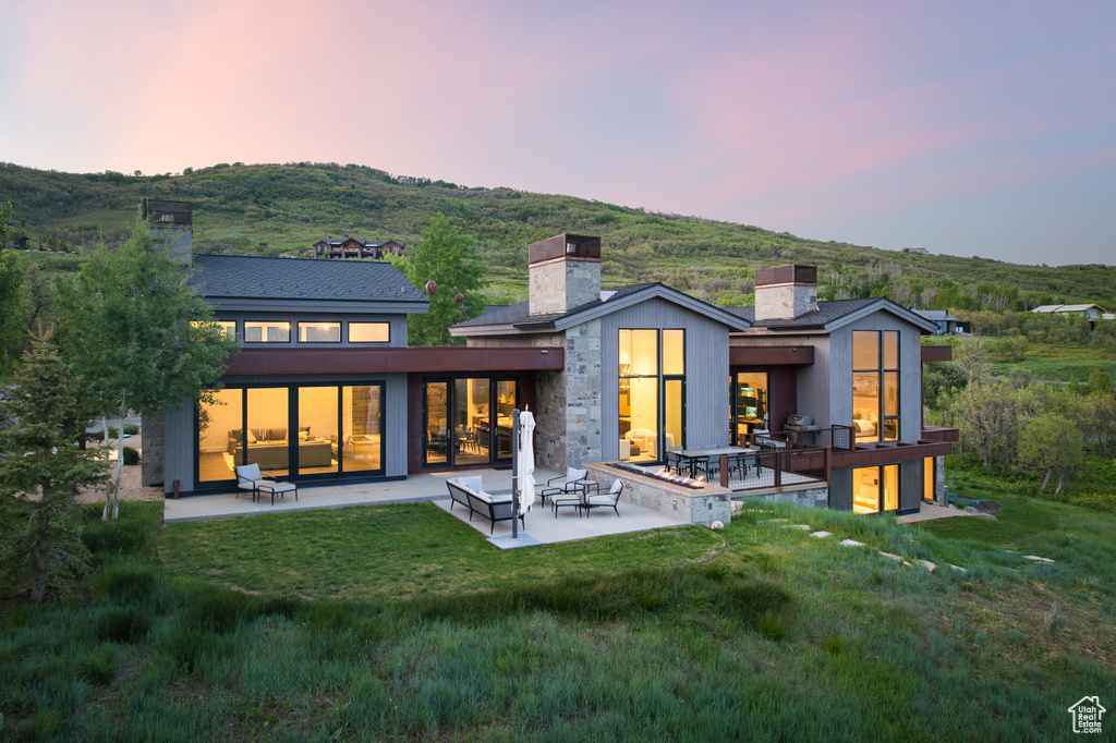 Rear view of house featuring a chimney, a patio, and a yard