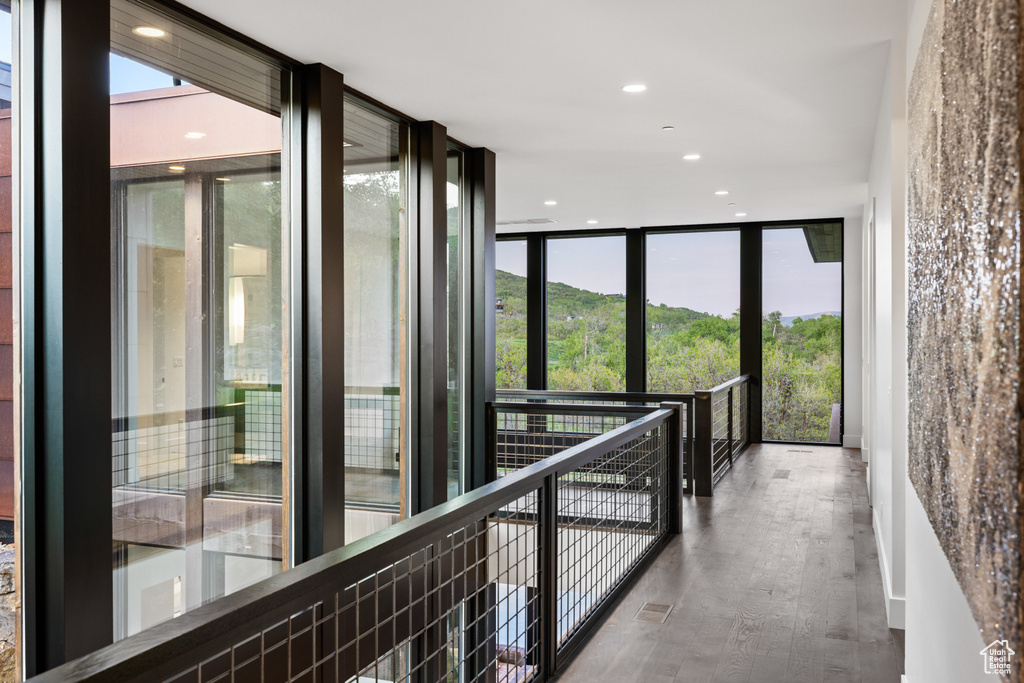 Corridor featuring expansive windows, wood finished floors, and recessed lighting