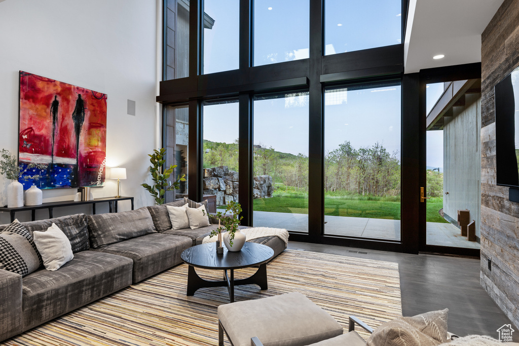 Living area featuring a high ceiling, healthy amount of natural light, wood finished floors, and recessed lighting