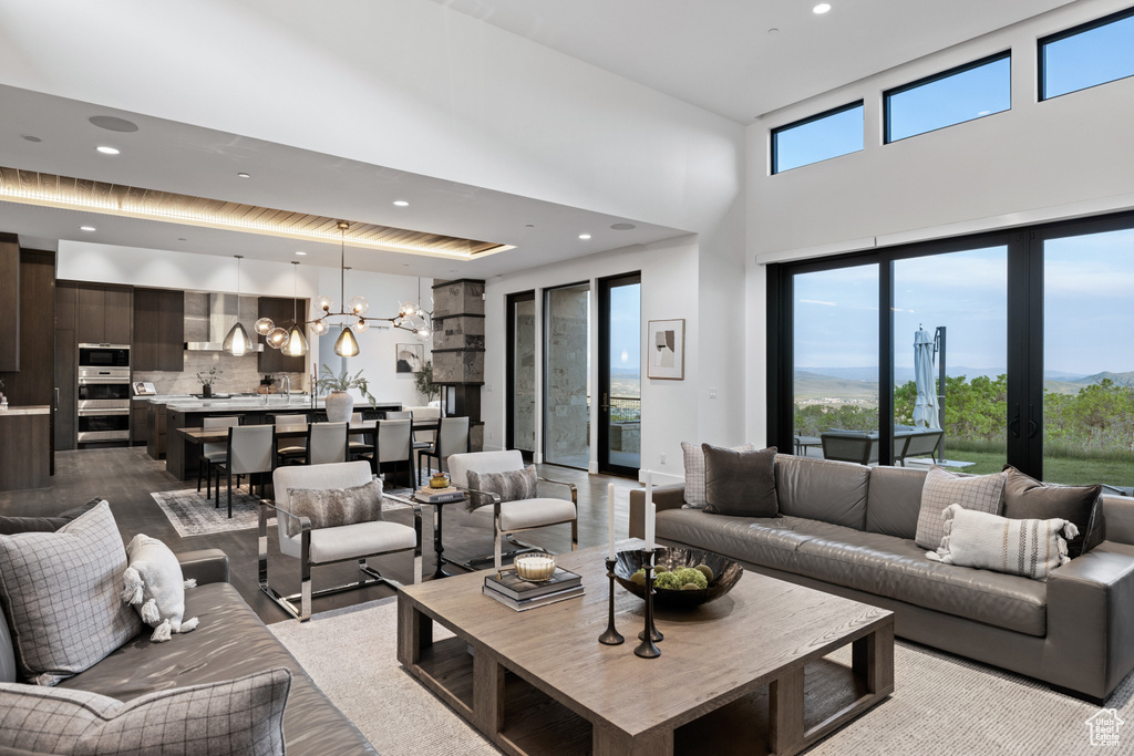 Living room with recessed lighting, a high ceiling, wood finished floors, and a chandelier