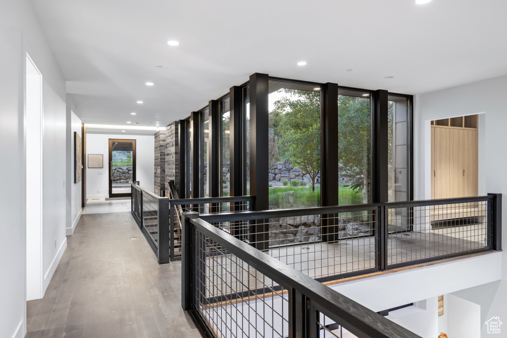 Corridor with an upstairs landing, recessed lighting, wood finished floors, baseboards, and a wall of windows