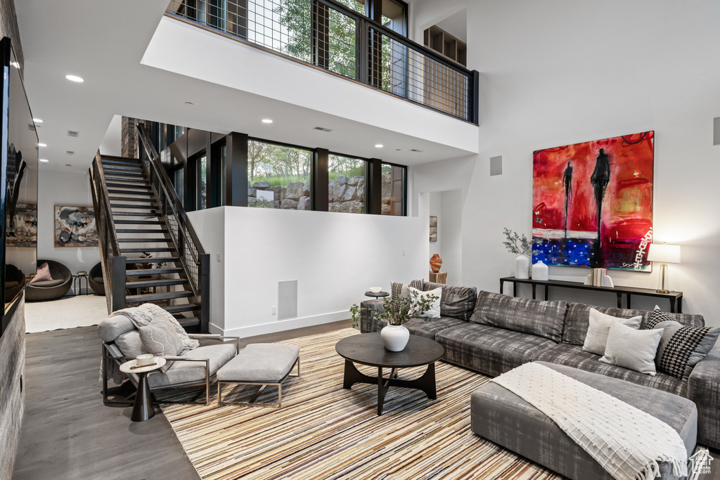 Living area with a high ceiling, stairway, wood finished floors, and recessed lighting