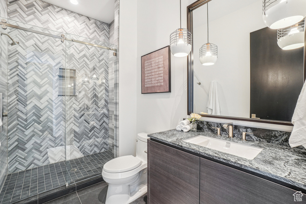 Full bathroom with toilet, vanity, tile patterned flooring, and a stall shower