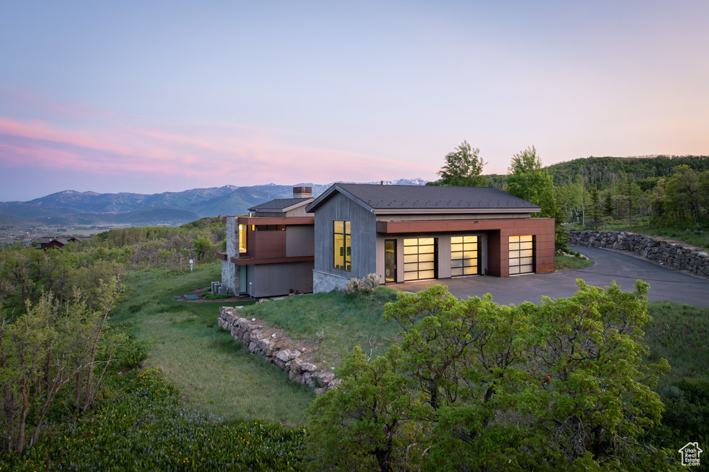 View of front of house with a garage, a mountain view, a front yard, and a chimney