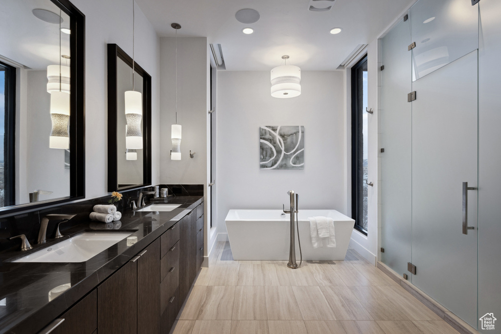 Full bath with a freestanding tub, double vanity, a shower stall, and baseboards