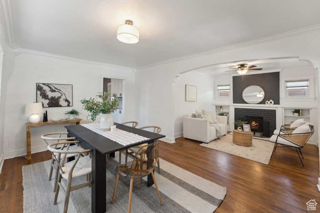Dining room featuring crown molding, arched walkways, ceiling fan, and wood finished floors
