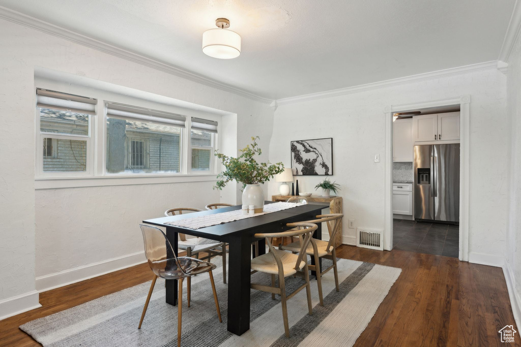 Dining space with baseboards, ornamental molding, dark wood-style flooring, and visible vents