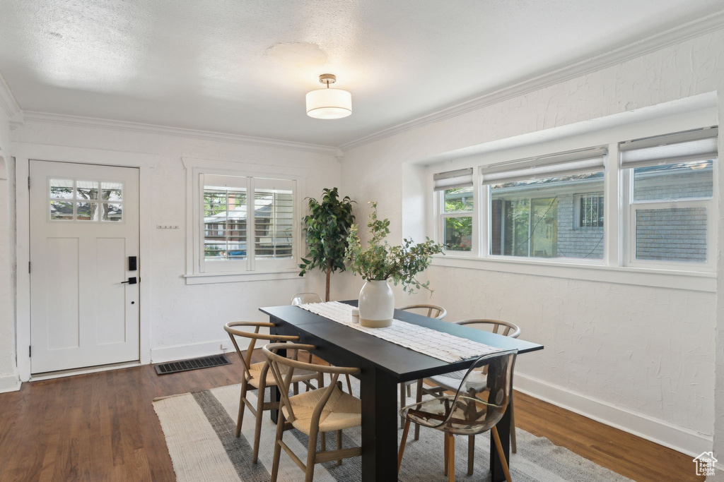 Dining area with baseboards, ornamental molding, wood finished floors, and visible vents