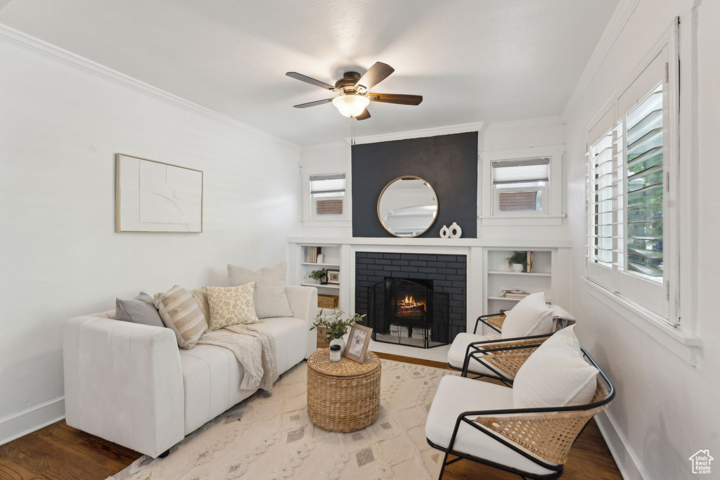 Living room featuring crown molding, a ceiling fan, baseboards, and a fireplace