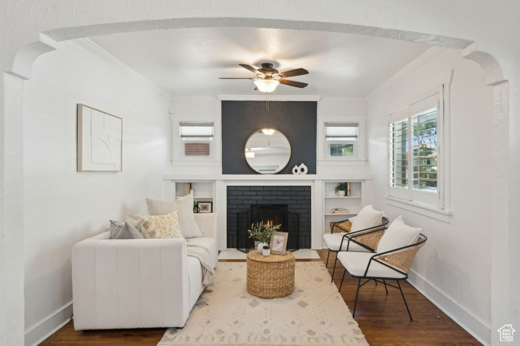 Living room featuring crown molding, a ceiling fan, baseboards, and wood finished floors