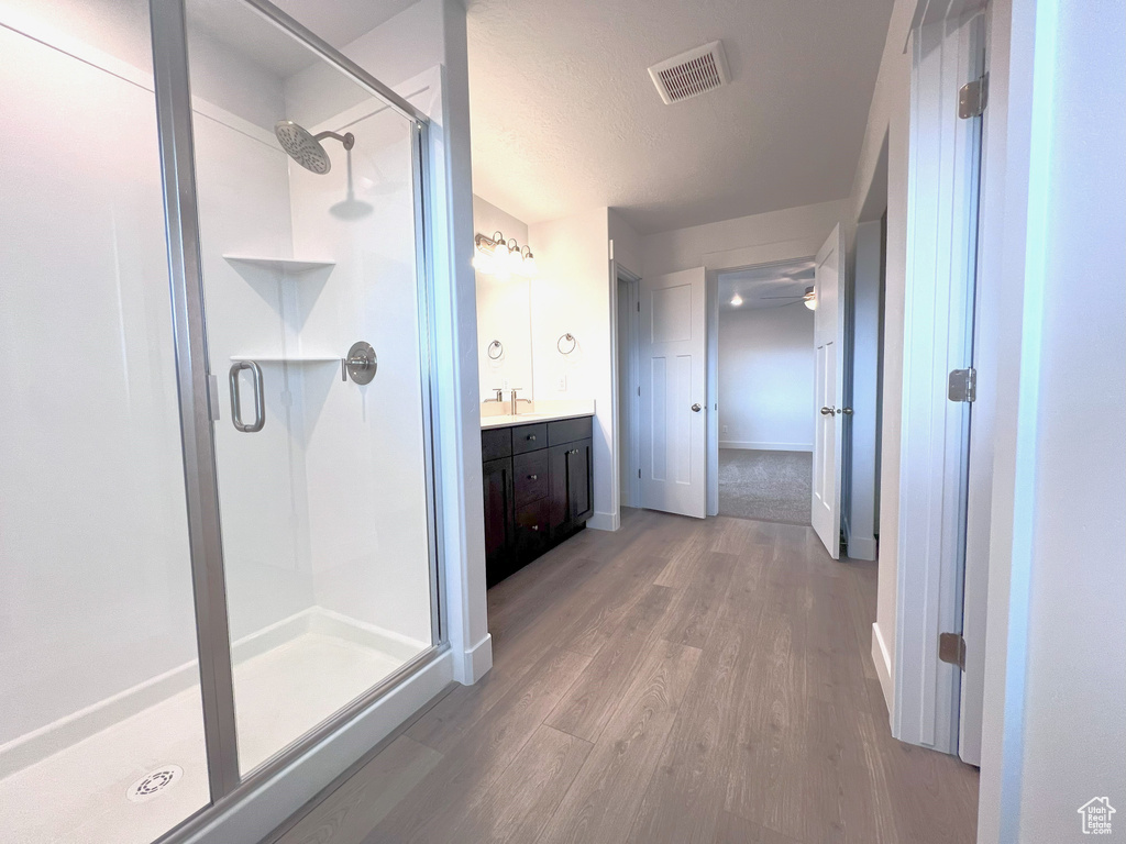 Full bathroom featuring visible vents, a shower stall, baseboards, wood finished floors, and vanity