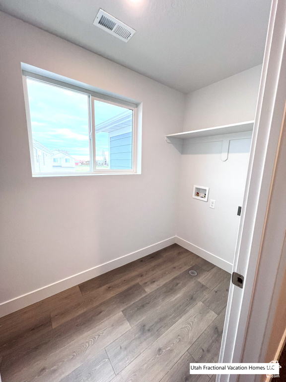 Washroom with visible vents, wood finished floors, baseboards, hookup for a washing machine, and laundry area