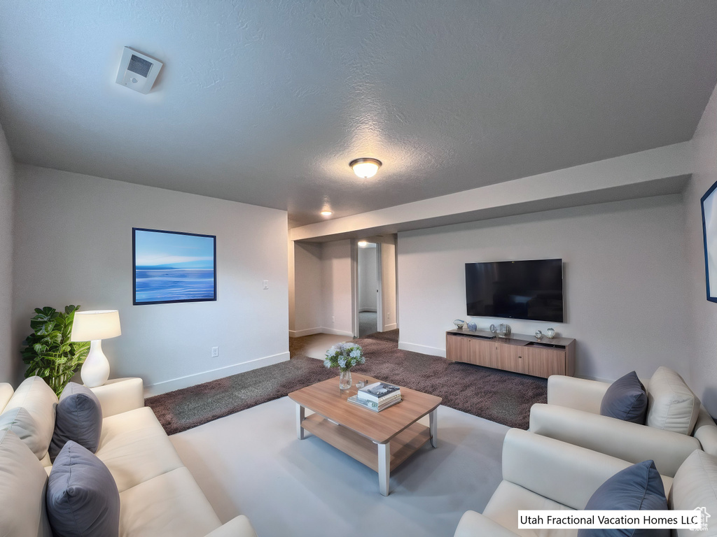 Living area with baseboards, a textured ceiling, and carpet flooring