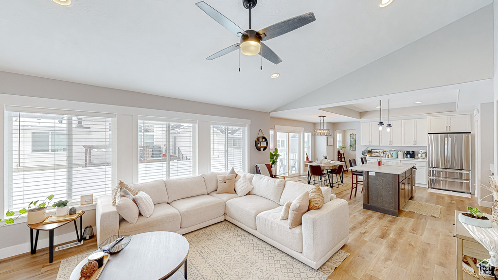 Living room with baseboards, light wood-type flooring, vaulted ceiling, recessed lighting, and a ceiling fan