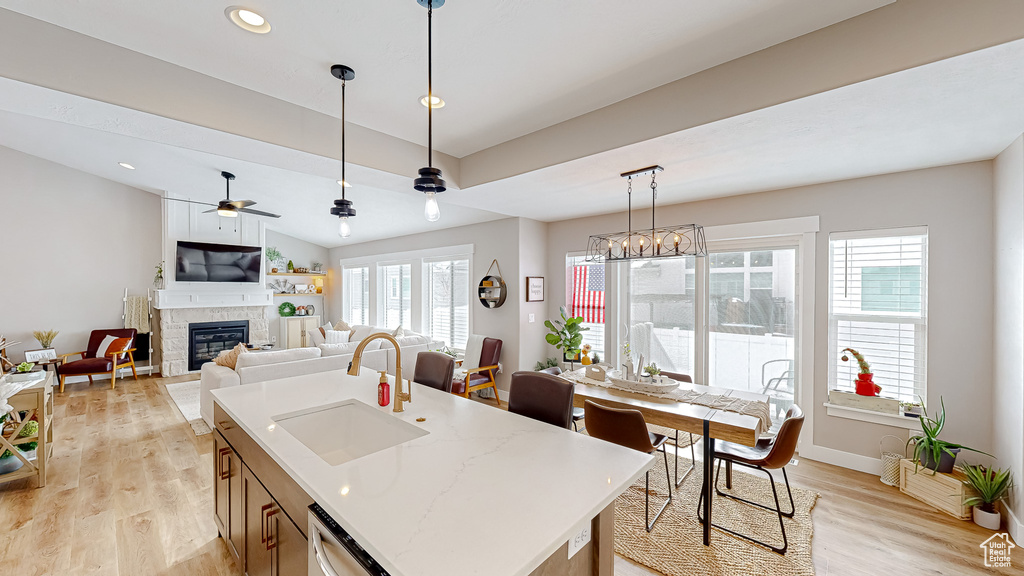 Kitchen with dishwashing machine, light wood-style flooring, a fireplace, ceiling fan, and a sink