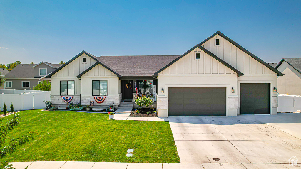 Modern farmhouse with fence, driveway, an attached garage, a front lawn, and board and batten siding