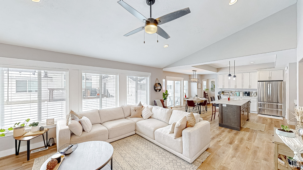 Living room with light wood finished floors, baseboards, ceiling fan, lofted ceiling, and recessed lighting