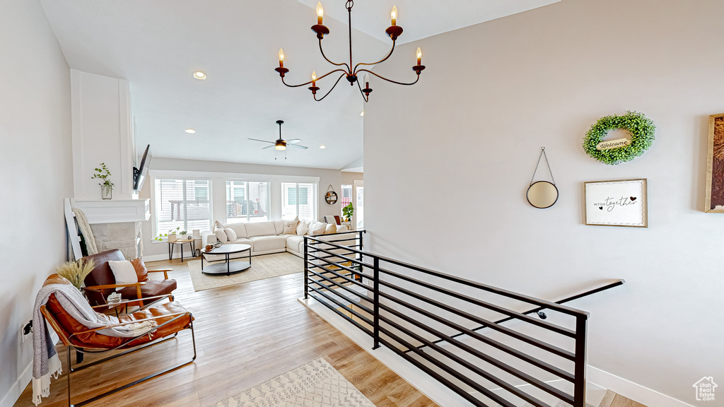 Interior space with wood finished floors, baseboards, recessed lighting, a fireplace, and ceiling fan with notable chandelier