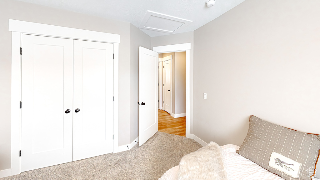 Bedroom featuring a closet, baseboards, attic access, and carpet