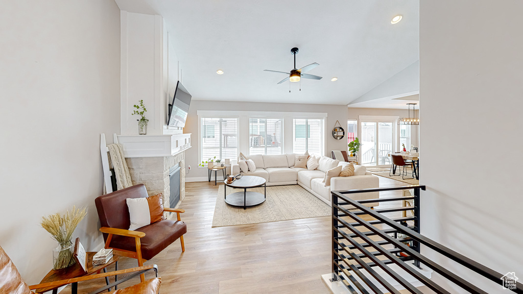 Living area featuring light wood finished floors, lofted ceiling, recessed lighting, a fireplace, and a ceiling fan