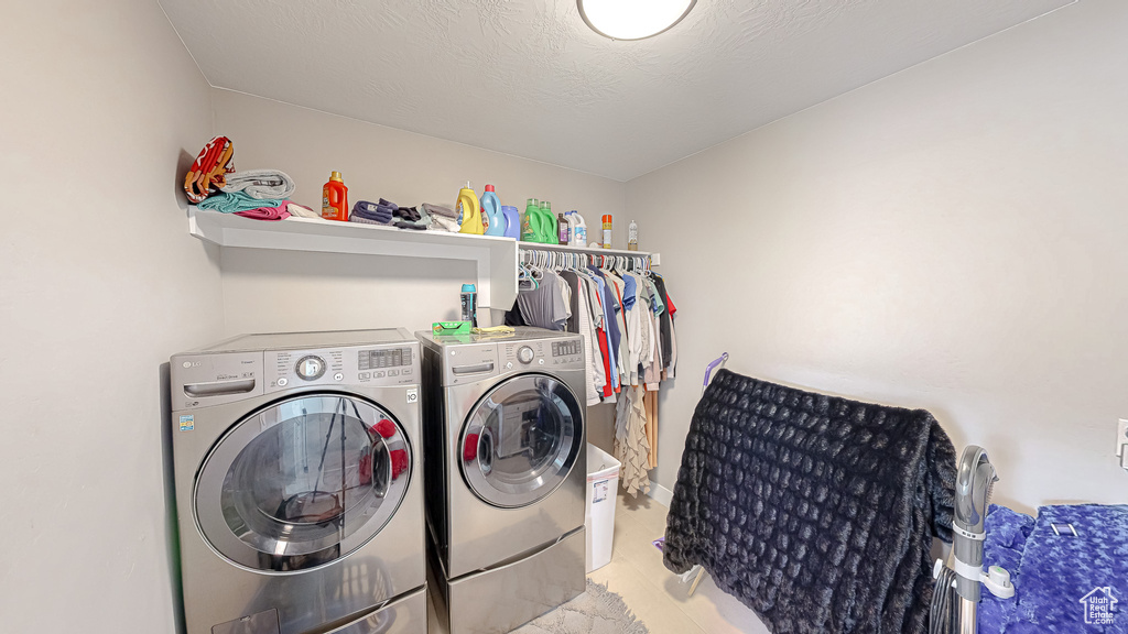 Laundry room with laundry area, washer and dryer, and a textured ceiling