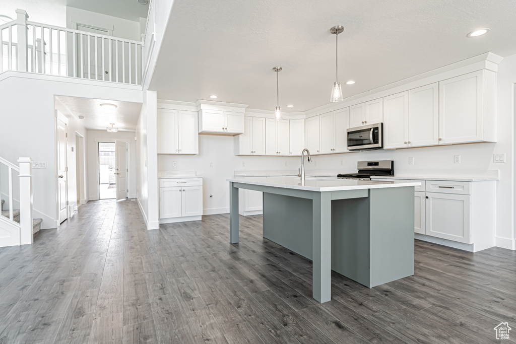 Kitchen with appliances with stainless steel finishes, wood finished floors, white cabinetry, and recessed lighting