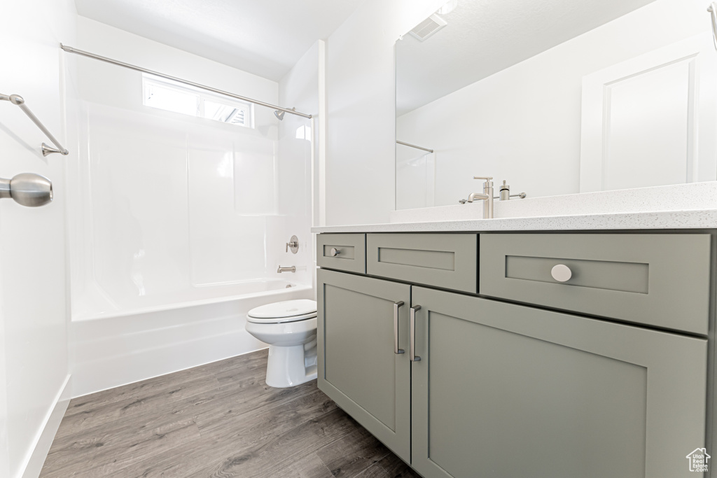 Bathroom with vanity, toilet, bathtub / shower combination, and wood finished floors