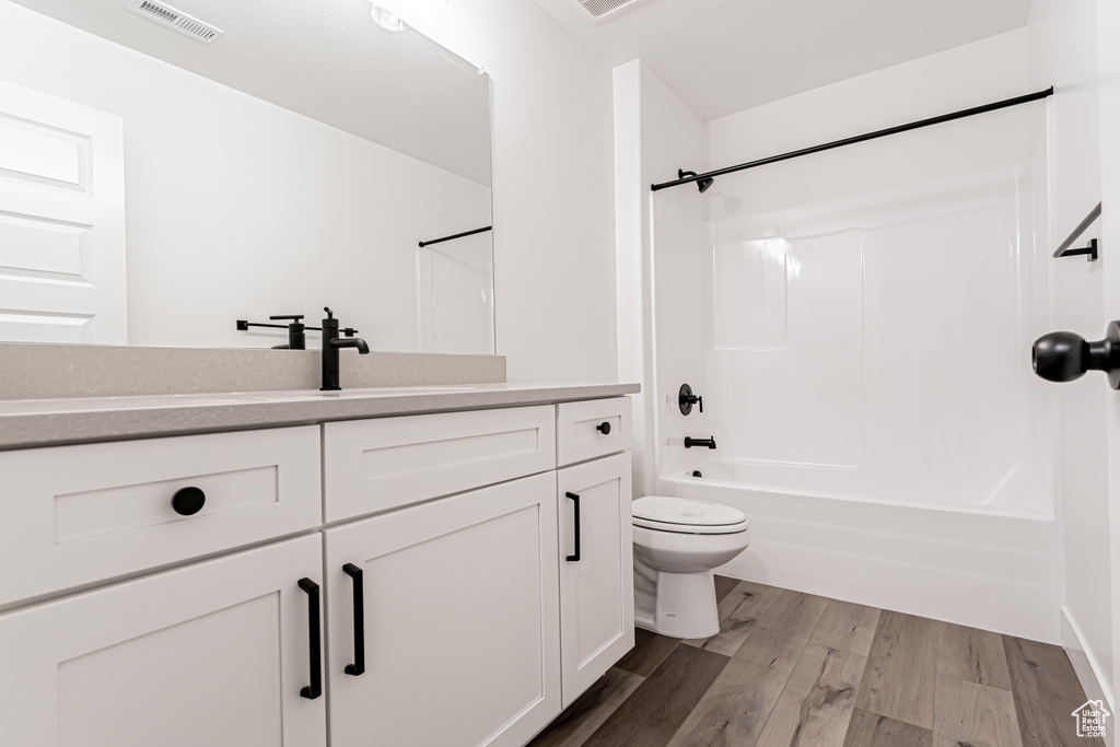 Bathroom with vanity, wood finished floors, and shower / bathtub combination