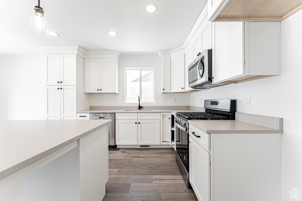 Kitchen featuring stainless steel appliances, recessed lighting, light countertops, white cabinets, and dark wood-style floors