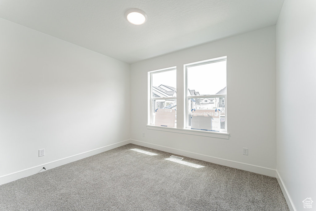 Spare room featuring carpet and baseboards