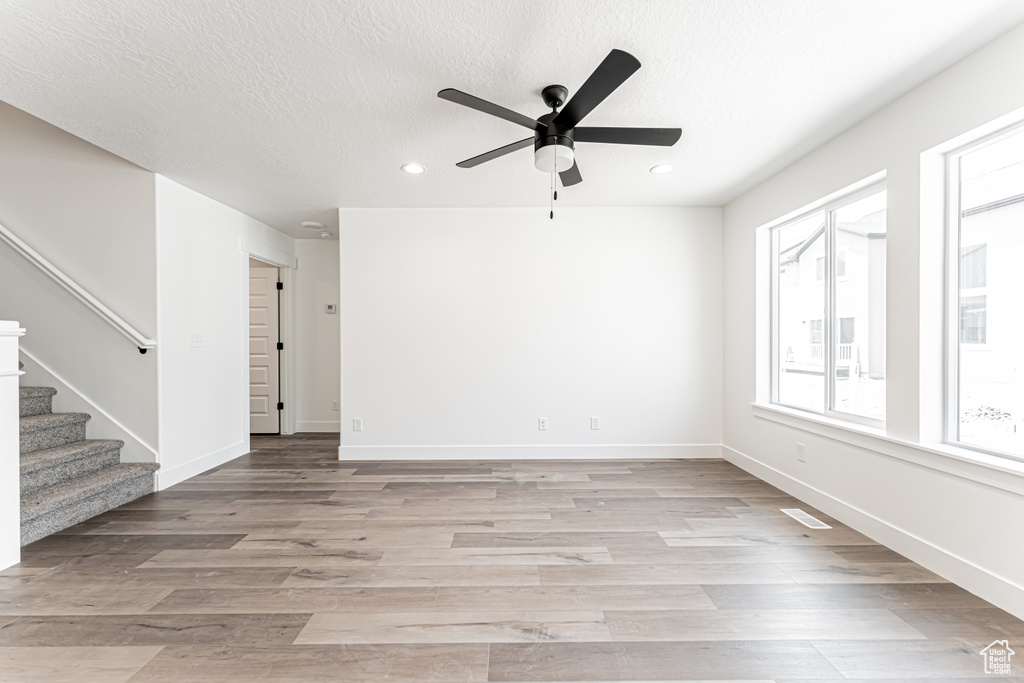 Spare room featuring stairway, recessed lighting, a ceiling fan, light wood-style flooring, and a textured ceiling