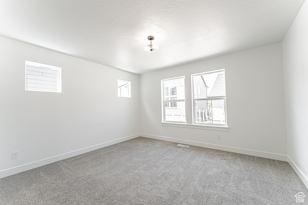 Spare room featuring light colored carpet and a textured ceiling