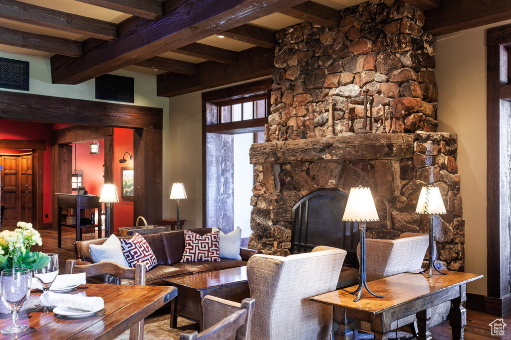 Living area featuring beam ceiling, wood finished floors, and a stone fireplace