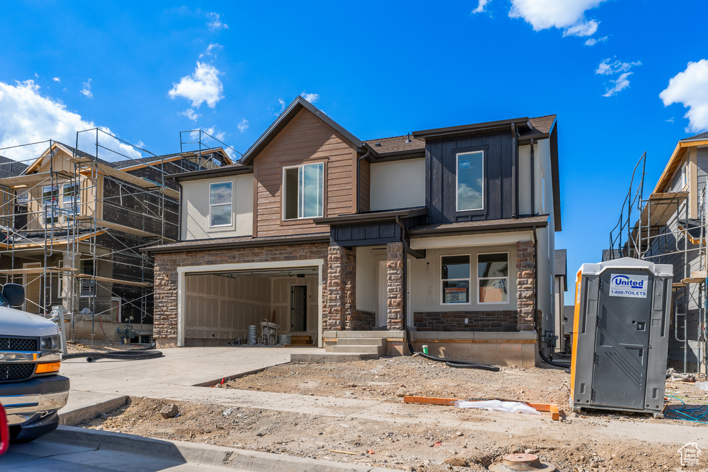 View of front facade with stone siding, concrete driveway, an attached garage, and board and batten siding