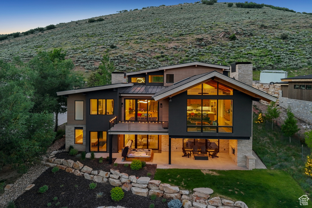 Back of house with a patio, a chimney, a standing seam roof, and a metal roof