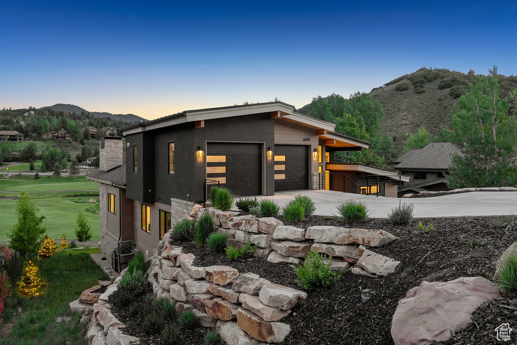 View of front of property featuring a mountain view, a garage, driveway, and a front yard