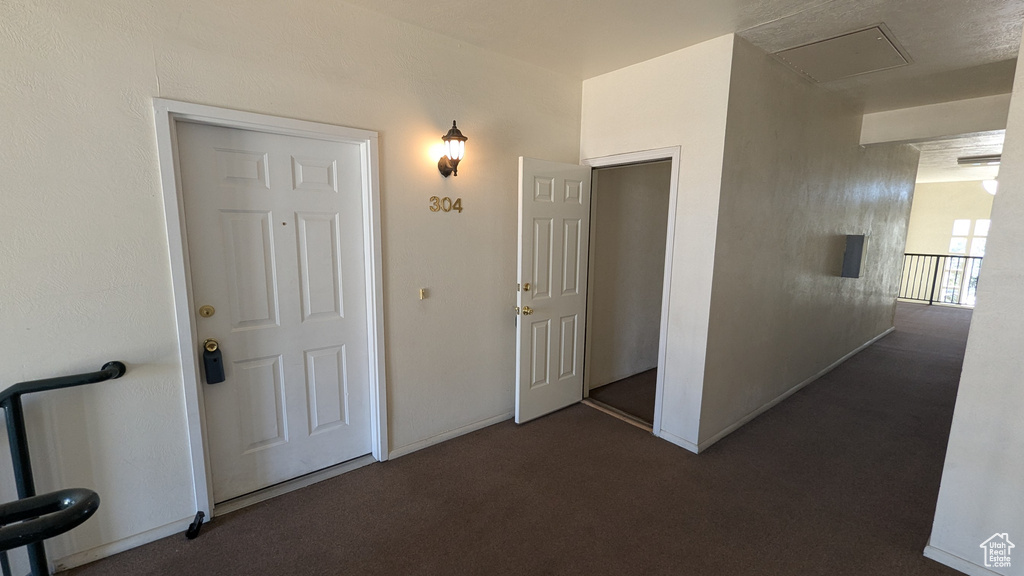 Corridor featuring dark colored carpet