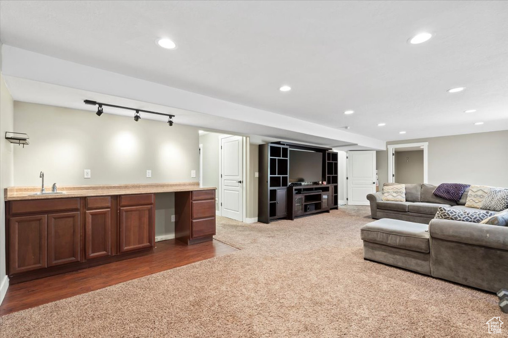 Carpeted living room featuring a sink, recessed lighting, wet bar, rail lighting, and baseboards