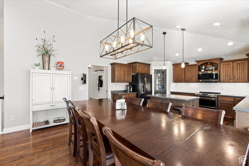 Dining space featuring lofted ceiling, dark wood finished floors, recessed lighting, baseboards, and a chandelier