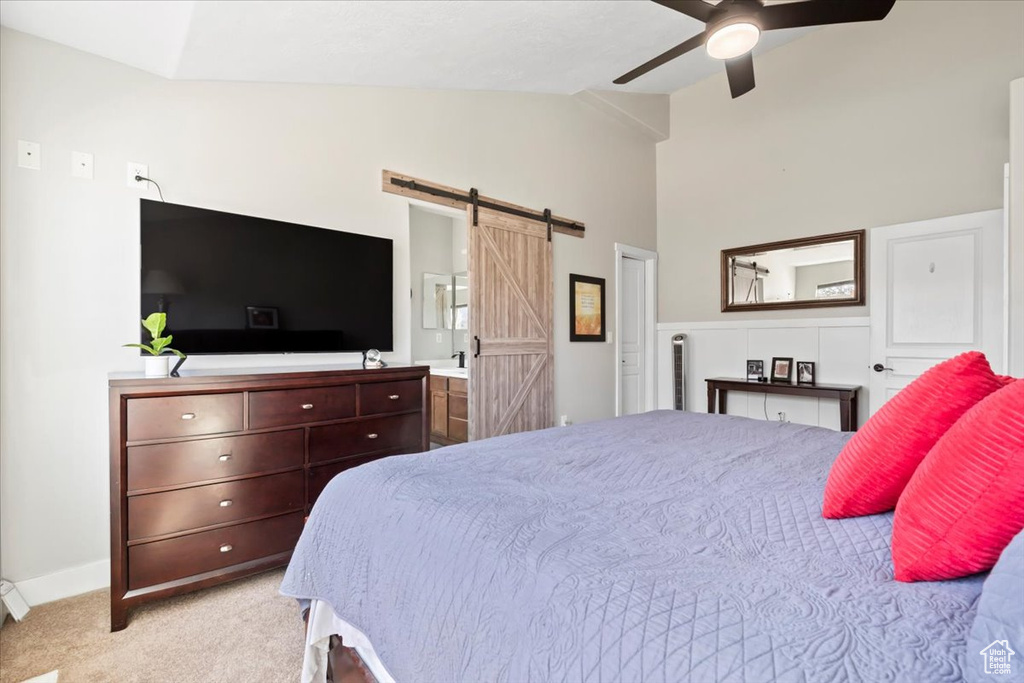 Carpeted bedroom featuring ceiling fan, baseboards, a barn door, and vaulted ceiling