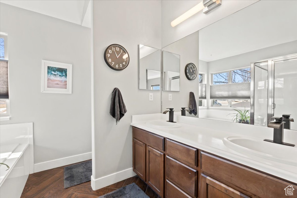 Full bathroom featuring double vanity, a garden tub, baseboards, and a sink