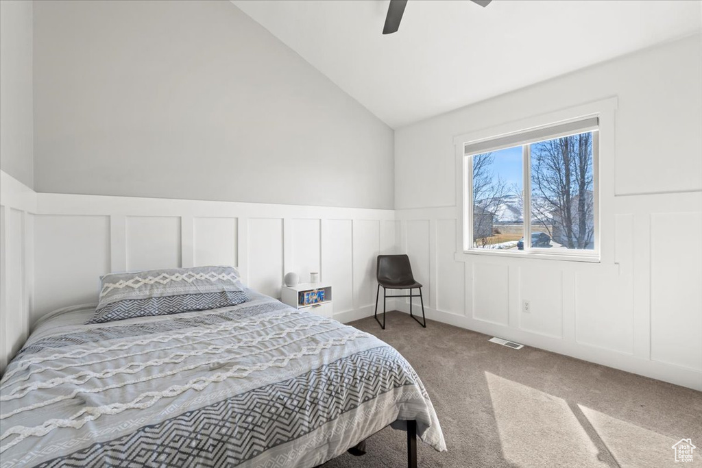 Carpeted bedroom featuring visible vents, a decorative wall, and lofted ceiling