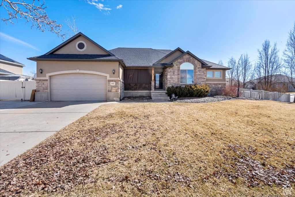 Ranch-style home featuring fence, concrete driveway, stucco siding, a garage, and stone siding