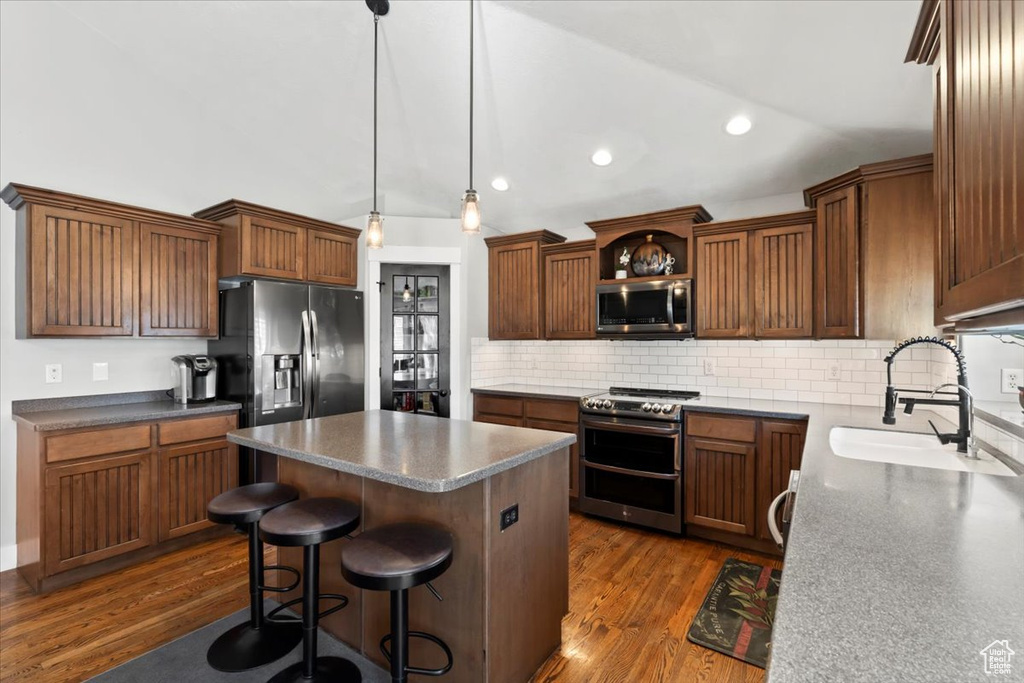 Kitchen featuring a kitchen island, dark wood finished floors, a sink, stainless steel appliances, and vaulted ceiling