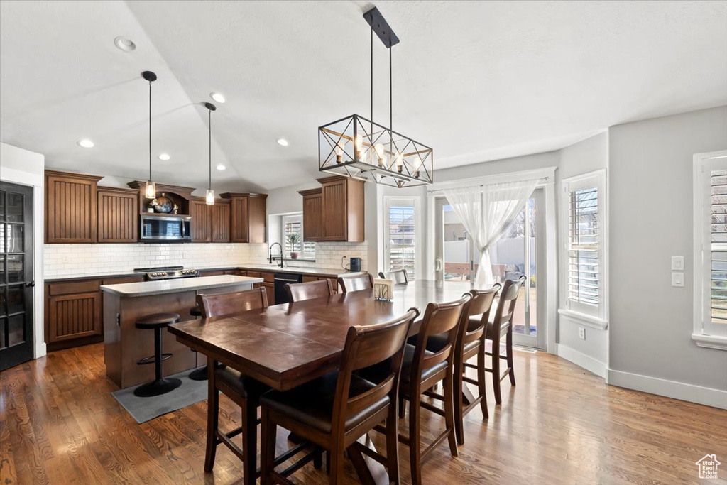 Dining room with a notable chandelier, recessed lighting, wood finished floors, and baseboards