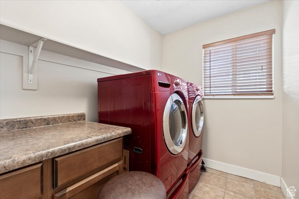 Washroom with light tile patterned floors, baseboards, and independent washer and dryer