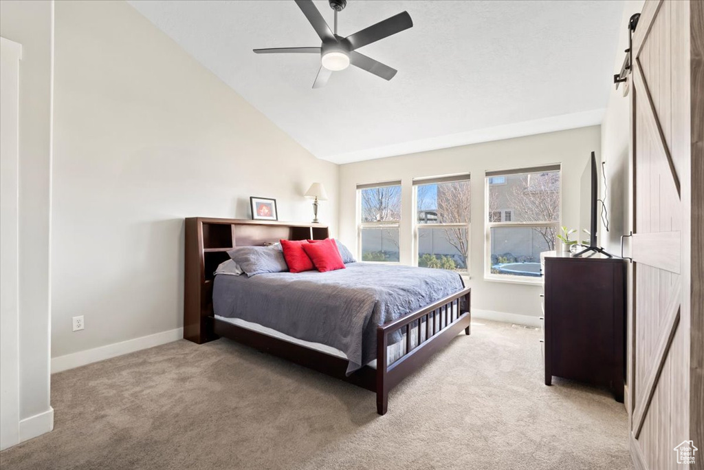 Carpeted bedroom with ceiling fan, baseboards, lofted ceiling, and a barn door